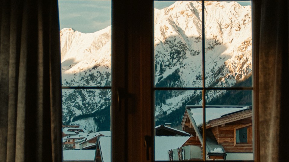 Vue sur des sommets enneigés et des chalets à travers une fenêtre parfaitement nette